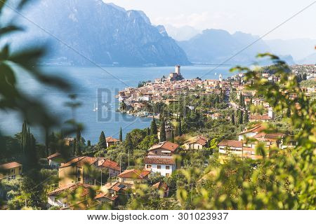 Idyllic Coastline Scenery In Italy: Blue Water And A Cute Village At Lago Di Garda, Malcesine