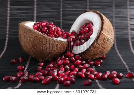 Garnet Seeds In Coconut Shell In Black Wood Background