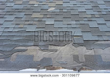 Сlose Up View Of Bitumen Shingles Roof Damage That Needs Repair.