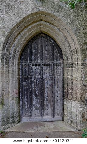 Ancient Wooden Door Set Into A Stone Surround.  Door Has Lovely Black Metal Patterned Clasp And Stud