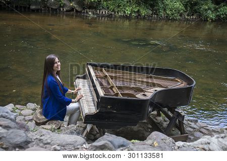 Abandoned Gran Piano, Rundown Piano By A River Bank (vilnia River) In Uzupis Artists Quarter In Viln