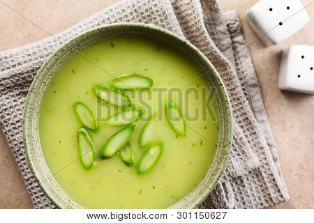 Cream Of Green Asparagus Soup In Bowl, Garnished With Sliced Asparagus On Top, Photographed Overhead
