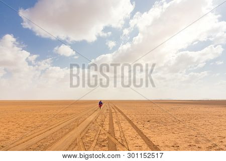 Solitary Masai Worrior Walking Along Salt Lake Desert Road In Kenya, Amboseli Natural Park, Africa