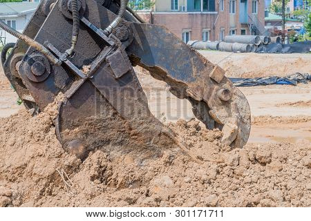 Closeup Of Unattached Hydraulic Backhoe Jaw At Rest In Mound Of Dirt At Construction Site.