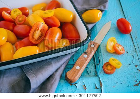 Small Cherry Tomatoes, Red And Yellow, In An Enameled Baking Sheet On A Blue Background