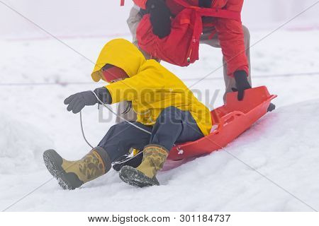 Father Is Helping Her Daughter To Ride The Snow Sled