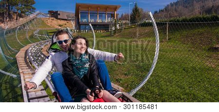 Excited young couple driving alpine coaster while enjoying beautiful sunny day in the nature