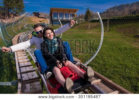 Excited young couple driving alpine coaster while enjoying beautiful sunny day in the nature