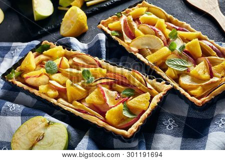 French Pineapple And Apple Sweet Open Tarts In Rectangular Tart Pans On A Concrete Table With Kitche