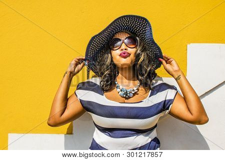 A Beautiful African Woman In A Blue And White Striped Dress Modelling In Front Of A Traditional Bo-k