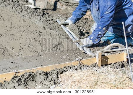 Pool Construction Worker Working With A Smoother Rod On Wet Concrete