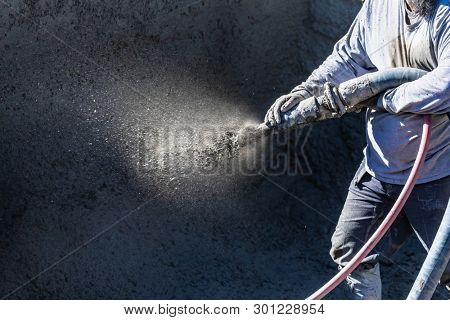 Pool Construction Worker Shooting Concrete, Shotcrete or Gunite Through Hose