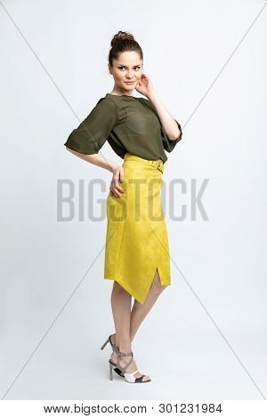 Model In Green Blouse, Yellow Suede Skirt With Yellow Belt, White Heeled Sandals Isolated On White B