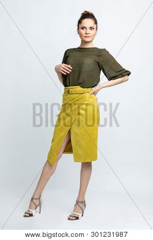 Model In Green Blouse, Yellow Suede Skirt With Yellow Belt, White Heeled Sandals Isolated On White B