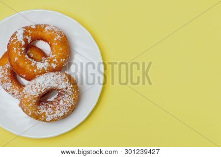 Appetizing Donuts With Icing Sugar On A White Plate On A Bright Yellow Background, Plenty Of Space F