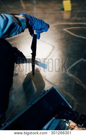 Partial View Of Investigator Putting Evidence In Ziploc Bag At Crime Scene