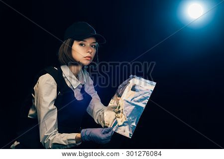 Investigator In Rubber Gloves Holding Ziploc Bag With Dollar Banknote At Crime Scene