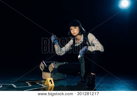Investigator In Uniform Holding Knife And Ziploc Bag At Crime Scene