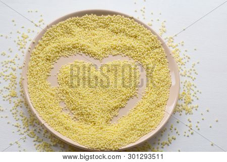 Dry Couscous On A Plate On A White Background. Spilled Couscous. Raw Couscous Close-up