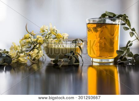 Bunch Of Flowers Of Drumstick On Wooden Surface Along With Its Extracted Water Or Tincture In A Glas