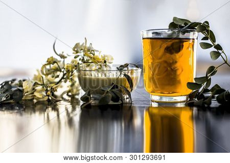 Bunch Of Flowers Of Drumstick On Wooden Surface Along With Its Extracted Water Or Tincture In A Glas