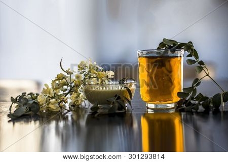 Bunch Of Flowers Of Drumstick On Wooden Surface Along With Its Extracted Water Or Tincture In A Glas