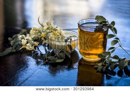 Bunch Of Flowers Of Drumstick On Wooden Surface Along With Its Extracted Water Or Tincture In A Glas