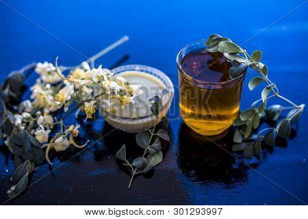 Bunch Of Flowers Of Drumstick On Wooden Surface Along With Its Extracted Water Or Tincture In A Glas