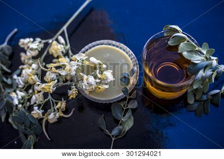 Bunch Of Flowers Of Drumstick On Wooden Surface Along With Its Extracted Water Or Tincture In A Glas