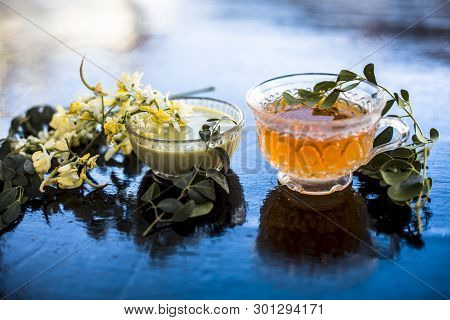 Bunch Of Flowers Of Drumstick On Wooden Surface Along With Its Extracted Tea And Paste Of Flowers In