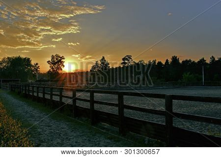 Sunset Rays Of The Sun Beautiful Against The Cloudy Sky Near The Place For Walking Horses