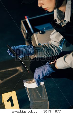 Cropped View Of Investigator Holding Knife And Ziploc Bag At Crime Scene