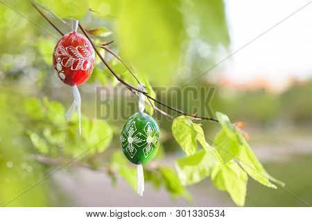Grean Easter Background With Painted Wooden Eggs Hanging From Tree Branches. This Image Is Blurred, 