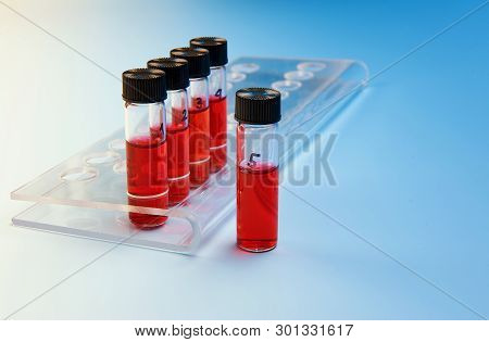 Three Liquid Samples In Plastic Vials In A Tube Stand On Blue Background