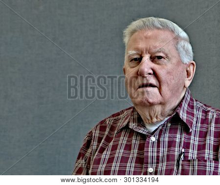 Senior Octogenarian Old Man In Plaid Shirt With Gray Background.