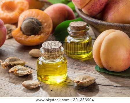Apricot kernel oil and apricot kernels on wooden background.