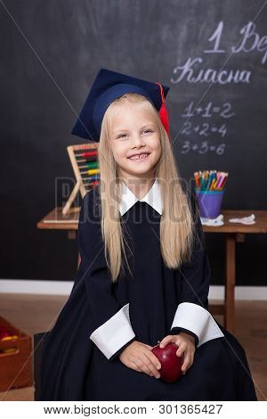 Back To School! Cheerful Little Girl At School On A Black Background. Looking Into The Camera. Schoo