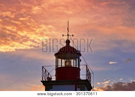 Lighthouse of Ponta do Altar on sunset sky background. West view over Praia da Afurada beach. Ferragudo, Lagoa, Algarve, Portugal