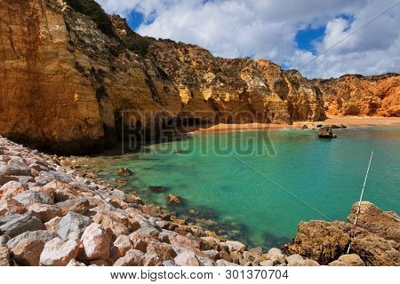 Summer beach scene at Algarve coast Pinhao beach, Lagos, Portugal. Stone cliff rocks, ocean water wunder blue sky