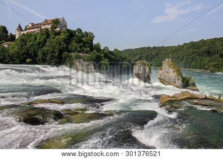 Rhine Falls With Calst Laufen At The Background. Rhine Falls Is The Biggest Plain Waterfall In Europ