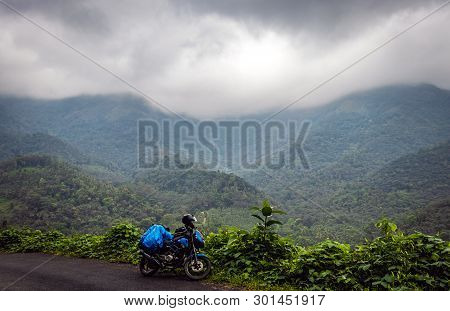In This Image Solo Traveller Ridding Love Of A Bike Is Expressed With Hills And Green Forests.