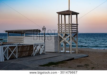 Sunset Seascape With White Wood Lifeguard Tower. Beach Landscape With Nobody. Retro Style Lifeguard 