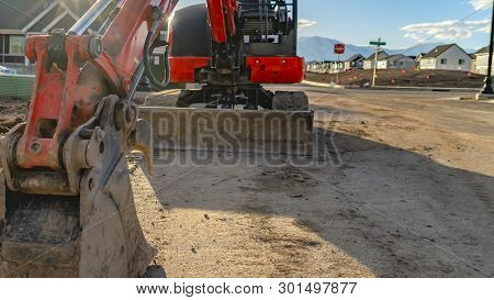 Panorama Close Up Of A Red Excavator With An Attched Grader Blade Viewed On A Sunny Day