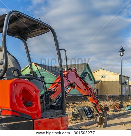Clear Square Red Excavator On A Construction Site For New Homes Against Cloudy Blue Sky