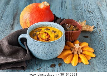 Pumpkin Soup Served In Blue Ceramic Cup With Pumpkin Seeds And Oil On Light Blue Rustic Table
