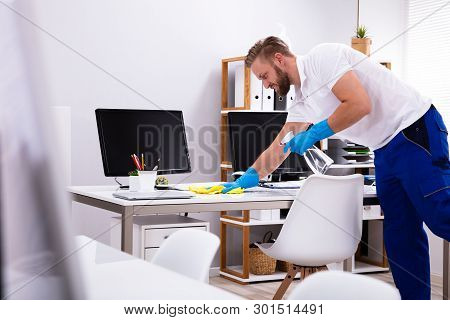 Janitor Cleaning White Desk In Modern Office