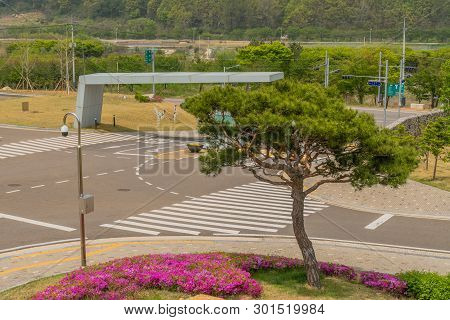 Muju,south Korea; May 1, 2019: Trimmed Evergreen Tree And Purple Azaleas On Corner Of Entrance Gate 