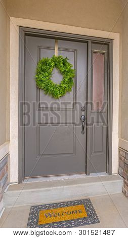 Vertical Gray Front Door Of A Home With A Simple Green Wreath And Sidelight