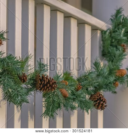 Clear Square Traditional Garland With Pine Cones Draped On The White Railing Of A Building