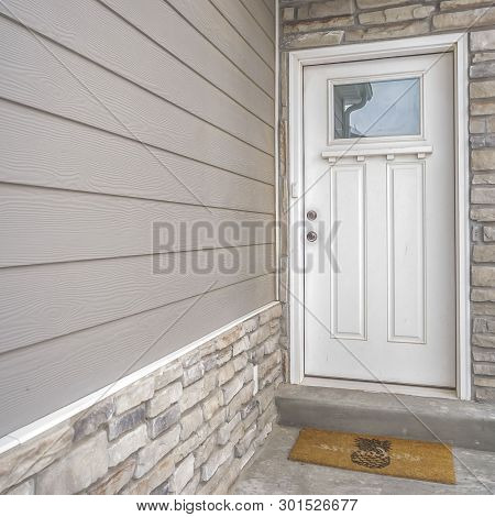 Square White Wooden Front Door With Reflective Glass Panel On The Entance Of A Home